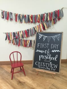 a first day of preschool sign next to a red chair with a chalkboard in front of it