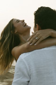 a man and woman embracing each other on the beach