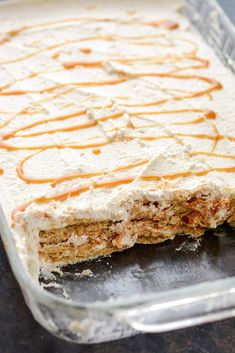 a cake with frosting and caramel drizzle on top in a glass dish