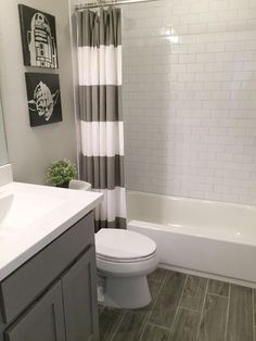 a white toilet sitting in a bathroom next to a bath tub under a window with gray and white curtains