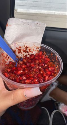 a person is holding a plastic container filled with cranberry sauce and strawberries