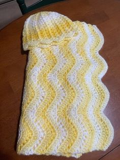 a yellow and white knitted sweater sitting on top of a wooden table