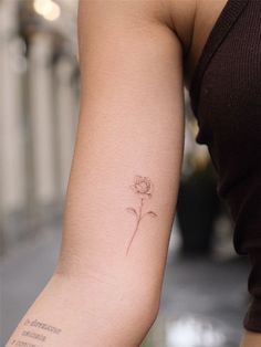 a woman's arm with a small flower tattoo on the left side of her arm