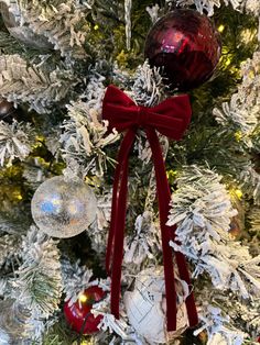 a christmas tree with ornaments hanging from it's sides and a red bow on the top