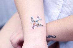 a small tattoo on the wrist of a woman with a mustache and an airplane drawn on it