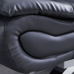 a black leather reclining chair sitting on top of a metal stand next to a wall