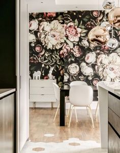 a kitchen with floral wallpaper and white chairs