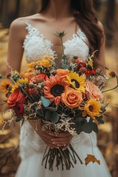 a woman holding a bouquet of sunflowers and other flowers in her hands,