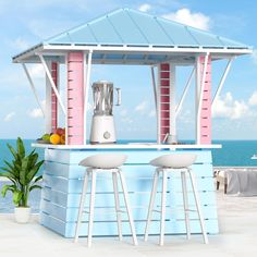 a blue and pink bar with two stools in front of the ocean on a sunny day