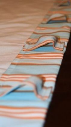 a close up view of a bed with blue and orange striped sheets