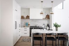 a kitchen with marble counter tops and black chairs in front of an island that is surrounded by white cabinets