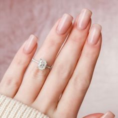 a woman's hand with a diamond ring on her left hand, wearing a white sweater