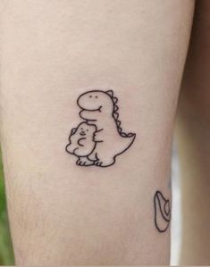 a small tattoo of a dinosaur holding a baby