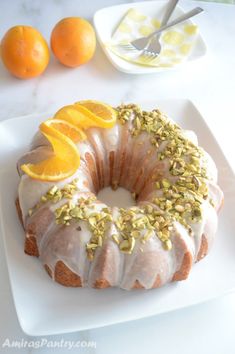 a bundt cake with oranges and pistachio on top sitting on a white plate