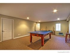 an empty room with a pool table and bar stools