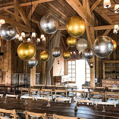 a room filled with lots of wooden tables and chairs covered in shiny balls hanging from the ceiling