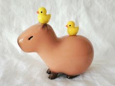 two yellow rubber ducks sitting on top of a toy hippopotamus, against a white background