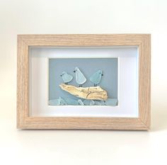 two birds sitting on a piece of driftwood in a shadow box with white background