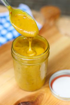 a spoon full of mustard sitting on top of a jar