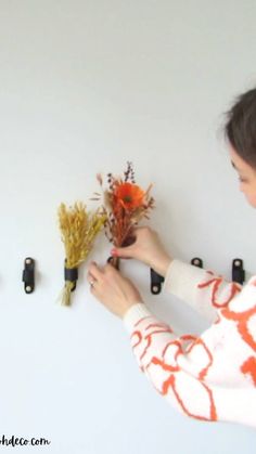 the woman is arranging flowers on the wall