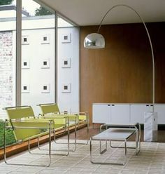 a living room filled with lots of furniture and large glass windows on the side of it