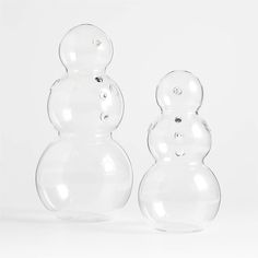 two clear glass snowmen sitting next to each other on a white surface with no background