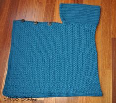 a blue knitted scarf laying on top of a wooden floor