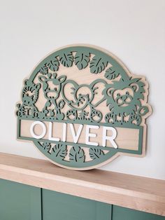 a wooden sign that says oliver on top of a shelf in front of a white wall