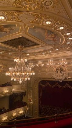 an ornately decorated auditorium with chandelier and red velvet seats