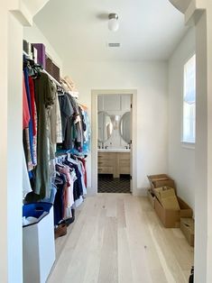 an open closet with clothes on hangers and boxes in the floor next to it