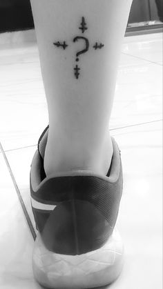 a person's foot with a question mark on the side of their ankle tattoo