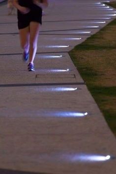 a woman running down a sidewalk at night