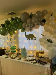 a table topped with lots of balloons and cake