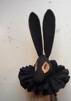 a black rabbit mask on top of a white wall