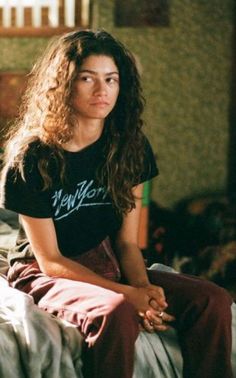 a young woman sitting on top of a bed