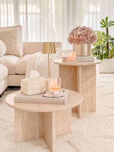 two tables with candles and flowers on them in a living room