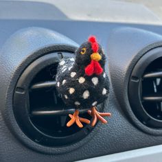 a stuffed chicken sitting in the center console of a car with its head on an air vent