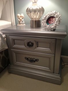 a nightstand with two drawers and a baby's picture frame on top of it