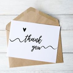 a thank card with the words thank you written in black ink on top of an envelope