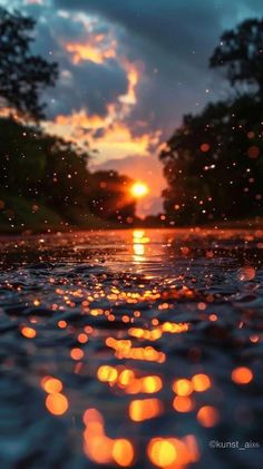 the sun is setting over some water with bubbles on it and trees in the background