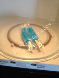 two blue toothbrushes sitting on top of a glass plate in front of a microwave