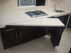 a white counter top sitting next to a sink in a kitchen with black cabinets and drawers