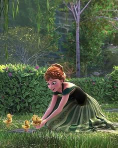 a woman kneeling down in the grass with ducks