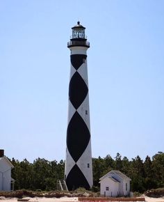 a black and white lighthouse sitting on top of a sandy beach