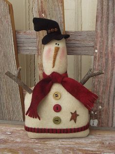 a snowman with a black hat and red scarf sitting on top of a wooden fence