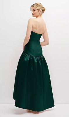 a woman in a green dress is looking back at the camera and she has her hands on her hips