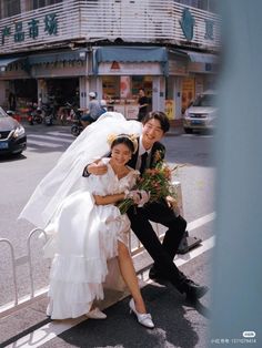 a bride and groom pose for a photo on the street