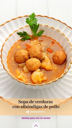 a bowl filled with soup and meatballs on top of a white table next to a plate