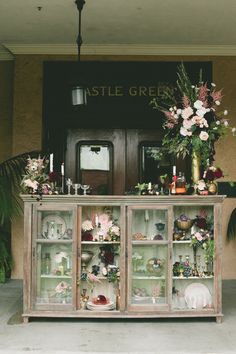 a display case filled with lots of flowers and greenery next to a building entrance