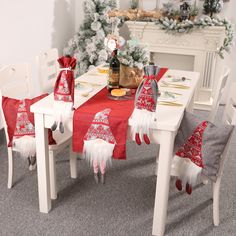 the table is set for christmas with red and white decorations on it, including santa's hats